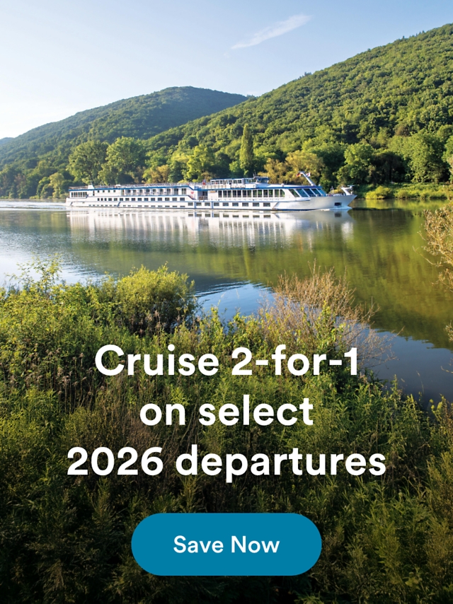 A white river cruise ship sailing along a calm, tree-lined river between forested hills. Overlaid text reads: "Cruise 2-for-1 on select 2026 departures" with a "Save Now" button.