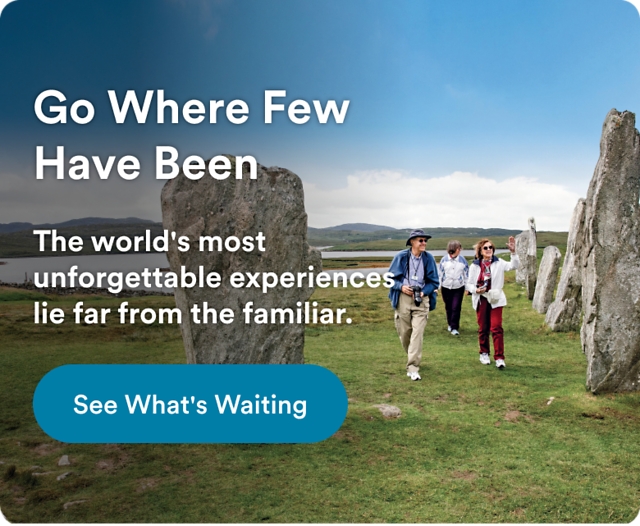 Travelers walking among ancient standing stones in a scenic landscape. Text reads: "Go Where Few Have Been. The world's most unforgettable experiences lie far from the familiar." Button: "See What's Waiting."
