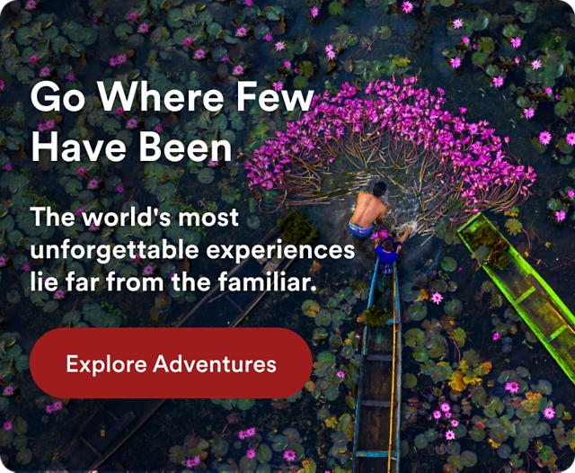 Aerial view of two people in a small boat harvesting pink water lilies in a lush wetland. Text reads: "Go Where Few Have Been. The world's most unforgettable experiences lie far from the familiar." Button: "Explore Adventures."
